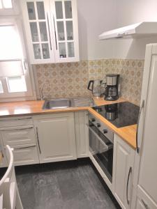 モンシャウにあるVIKARO Apartmentの白いキャビネットとシンク付きのキッチン