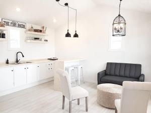 a living room with a black couch and a kitchen at The Fish Sheds in Rocky Harbour