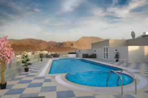 a pool on top of a building with mountains in the background at Al Murooj Grand Hotel in Muscat