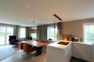 a kitchen and living room with a table and a dining room at Ulenhüs in Wenningstedt