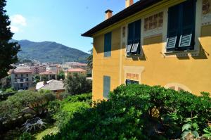 a yellow house with blue shutters on it at Villa Margherita in Levanto