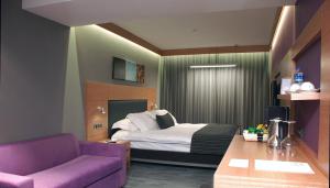 une chambre d'hôtel avec un lit et un canapé violet dans l'établissement Met Boutique Hotel, à Izmir