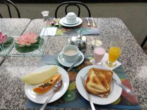 a table with a breakfast of toast and coffee and orange juice at Lodi Express Hotel in Arapongas
