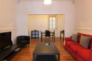 Lisbon City Center Apartment في لشبونة: غرفة معيشة مع أريكة حمراء وطاولة