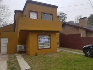 una casa amarilla con un cartel en la ventana en Departamento Alquiler Costa Azul para 5 personas en Costa Azul