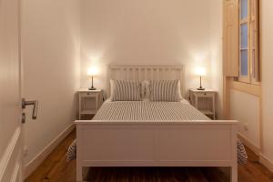 a white bed in a room with two lamps on tables at Lisbon City Center Apartment in Lisbon