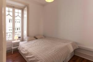 a white bedroom with a bed and a window at Lisbon City Center Apartment in Lisbon +12 photos