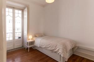 Lisbon City Center Apartment في لشبونة: غرفة نوم بيضاء بها سرير ونافذة