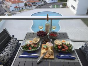 een tafel met borden en een fles wijn bij Silver Breezes Apartment in Nazaré