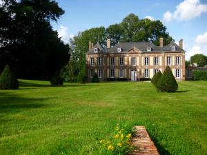 ein altes Herrenhaus mit einem großen Rasenplatz in der Unterkunft Château de Cleuville in Cleuville