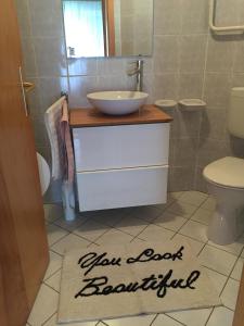 ヘーヴィーズにあるHolident Hévíz Apartmanのバスルーム(洗面台付)、バスルームの床にバスルームの看板が備わります。