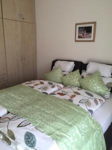 ヘーヴィーズにあるHolident Hévíz Apartmanのベッドルーム1室(ベッド2台、緑と白のシーツ付)