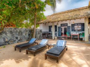 2 Liegestühle und ein Tisch vor einem Haus in der Unterkunft Red Parrot Beach Villa in Ambalangoda