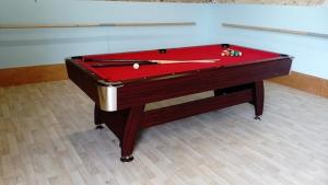 a pool table with a red cover in a room at Le Poirier Perfect for 2 adults and 2 children Heated Pool and Games Room in Auverse