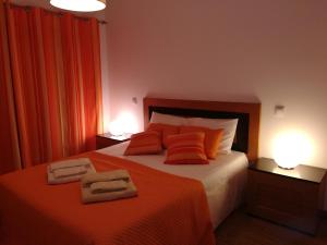 a bedroom with a bed with orange sheets and two lamps at Apartamento BaySide - São Martinho do Porto in São Martinho do Porto +61 photos