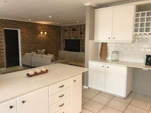 Una cocina con gabinetes blancos y una sala de estar. en Villa Bon Chretien, en Stellenbosch