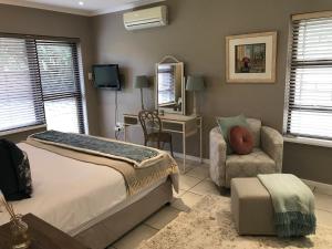 Un dormitorio con una cama, una silla y un escritorio. en Villa Bon Chretien, en Stellenbosch