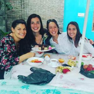 un grupo de tres mujeres sentadas en una mesa con comida en J hostel kandy, en Kandy