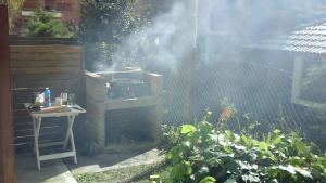 una parrilla en un jardín con humo saliendo de ella en Bungalow en Pinamar en Pinamar