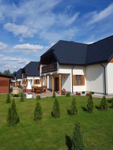 a house with a black roof and a yard at Apartamenty Białowieża in Białowieża