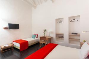 a hotel room with two beds and a television at Casa Oniri Hotel Boutique in Barichara