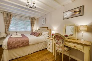 1 dormitorio con cama, escritorio y espejo en Coachhousebungalow, en Grange-over-Sands