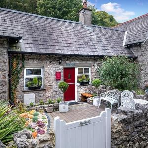 a stone house with a red door and a white fence at Coachhousebungalow in Grange Over Sands