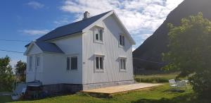 ein weißes Haus mit einem Hügel im Hintergrund in der Unterkunft Atlantic View Lofoten in Bøstad