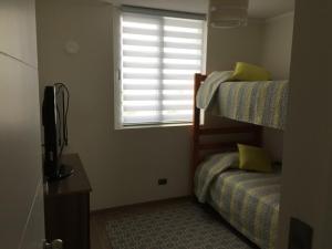 拉塞雷納的住宿－Departamento La Serena 6 Personas，一间卧室设有两张双层床和一扇窗户。