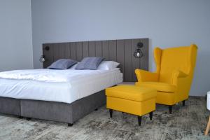 a bedroom with a bed and a yellow chair at SmartRooms in Olsztyn