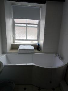 Una bañera blanca en un baño con ventana. en The Old Tea House, en Dorchester