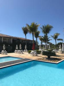 a swimming pool in front of a resort with palm trees at Búzios casa 41 in Búzios