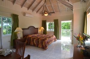 una camera da letto con un letto, un tavolo e alcune finestre di Tropical Lagoon Resort a Port Antonio