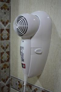 a white hair dryer in a corner of a bathroom at Hostal Carlos 2 in La Línea de la Concepción