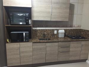 a kitchen with wooden cabinets and a microwave and a counter top at Apartamento em Canela in Canela