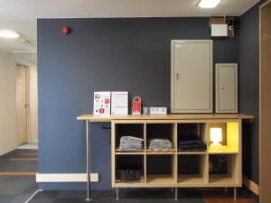 a room with a blue wall and a shelf with towels at Tsukuba Daily Inn in Tsukuba