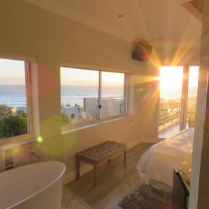 a bedroom with a bed and a view of the ocean at Gull on the Bay Boutique Guest House in Bloubergstrand