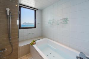 un bagno con vasca e finestra di HOTEL MYTH-Resort -ホテル マイス リゾート- adult only a Nagato