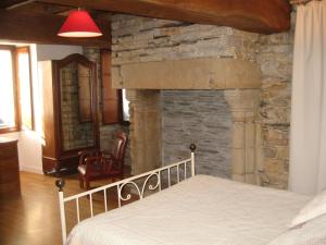 1 dormitorio con chimenea de piedra junto a la cama en Auberge Saint Hernin, en Pluherlin