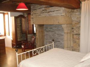 a bedroom with a stone fireplace next to a bed at Auberge Saint Hernin in Pluherlin