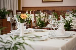 a table with glasses and plates and a vase with a flower at Garden Hotel Wellness és Konferencia in Szolnok