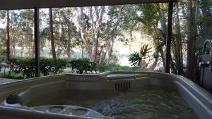 a bath tub filled with water in front of a window at Lake Russell Lakeside Retreat in Emerald Beach