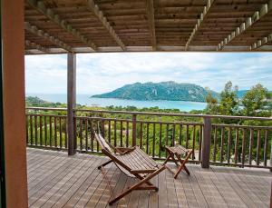 a deck with a chair and a view of the water at Résidence Les Hameaux de Santa Giulia in Porto-Vecchio
