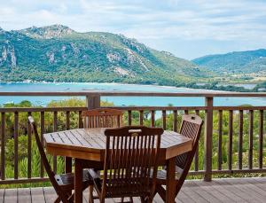 a wooden table and chairs on a deck with a view at Résidence Les Hameaux de Santa Giulia in Porto-Vecchio