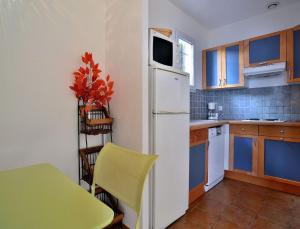 a kitchen with a table and a white refrigerator at Résidence Les Hameaux de Santa Giulia in Porto-Vecchio