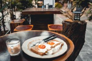 a plate of eggs and toast on a table with a glass of water at Sawatdee Guesthouse the Original in Bangkok