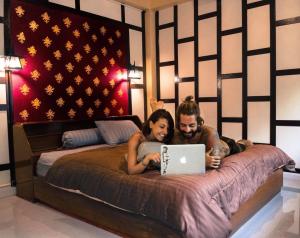 a man and woman laying on a bed with a laptop at Sawatdee Guesthouse the Original in Bangkok