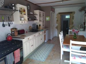 a kitchen with white cabinets and a table and a stove at Gite L'insinière in Saint-Martin-de-Chaulieu
