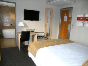 Habitación de hotel con cama, escritorio y TV. en Hôtel Saint-Pierre, en Vire