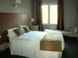 a hotel room with a large bed and a window at CIT'HOTEL Saint-Pierre in Vire